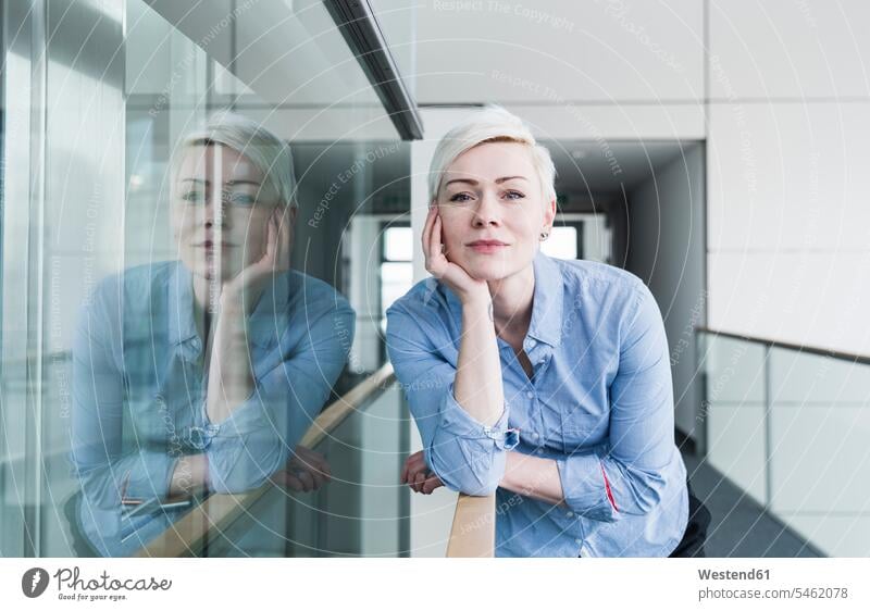 Porträt einer Frau auf der Büroetage, die sich an ein Geländer lehnt weiblich Frauen aufstützen aufgestuetzt aufgestützt Portrait Porträts Portraits Erwachsener
