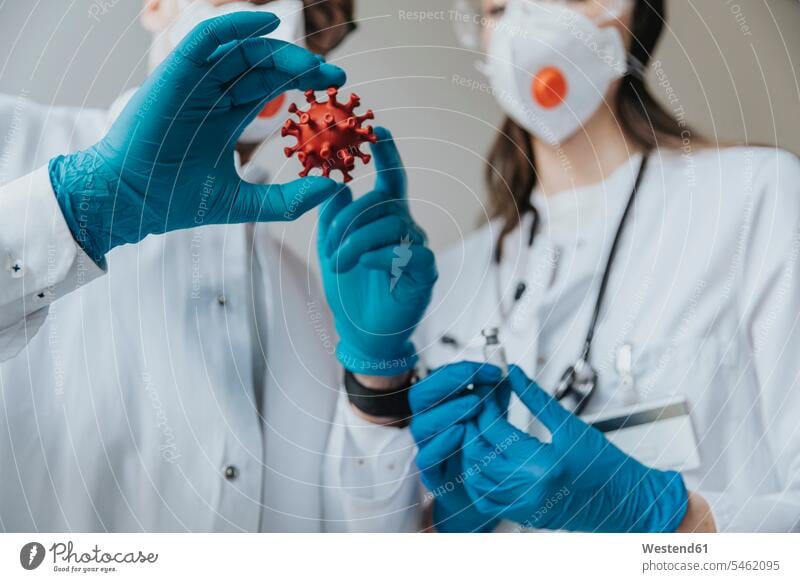Ärzte halten Modell einer biologischen Zelle und eines Impfstoffs im Krankenhaus Farbaufnahme Farbe Farbfoto Farbphoto Innenaufnahme Innenaufnahmen innen