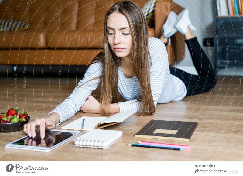 Junge Frau liegt zu Hause mit einer Tablette auf dem Boden Leute Menschen People Person Personen Alleinstehende Alleinstehender Singles Unverheiratete