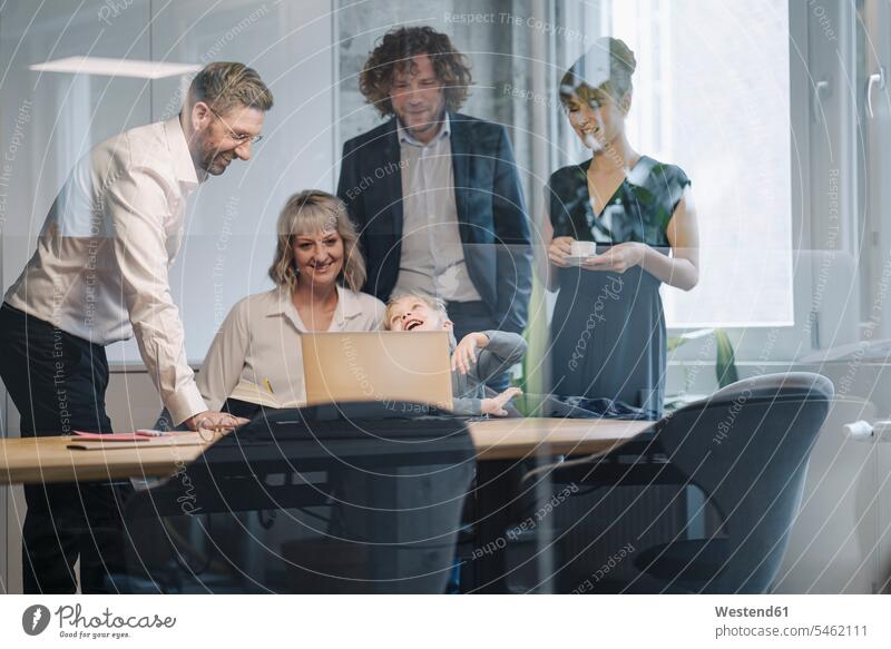 Geschäftsteam mit einem Jungen, der im Büro auf einen Laptop schaut Arbeitskollege Arbeitskollegen Kollege Job Berufe Berufstätigkeit Beschäftigung Jobs Boss