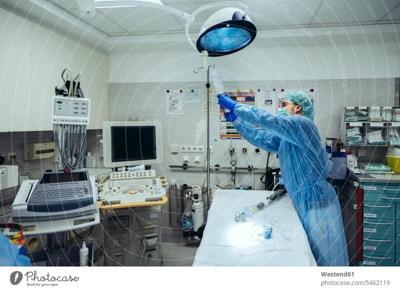 Arzt bereitet IV-Tropf im Traumaraum eines Krankenhauses vor Job Berufe Berufstätigkeit Beschäftigung Jobs Beleuchtungen Lampe Lampen Arbeit Gesundheit