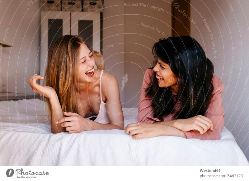 Freundinnen, die lachen, während sie im Bett liegen Farbaufnahme Farbe Farbfoto Farbphoto Innenaufnahme Innenaufnahmen drinnen Tag Tageslichtaufnahme