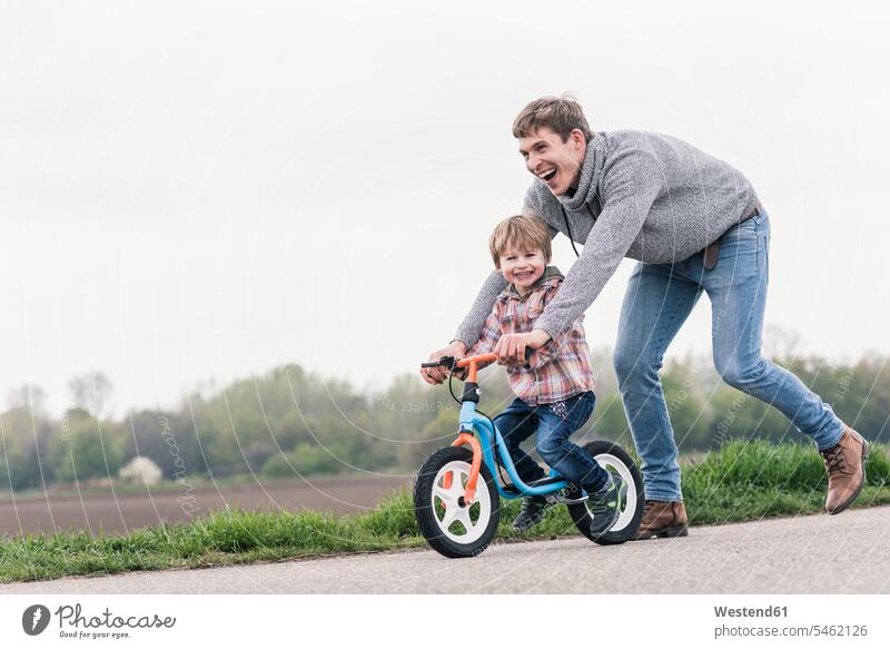 Vater bringt seinem Sohn das Fahrradfahren bei, im Freien Raeder Räder Bike Bikes Fahrräder Rad freuen Frohsinn Fröhlichkeit Heiterkeit Glück glücklich sein
