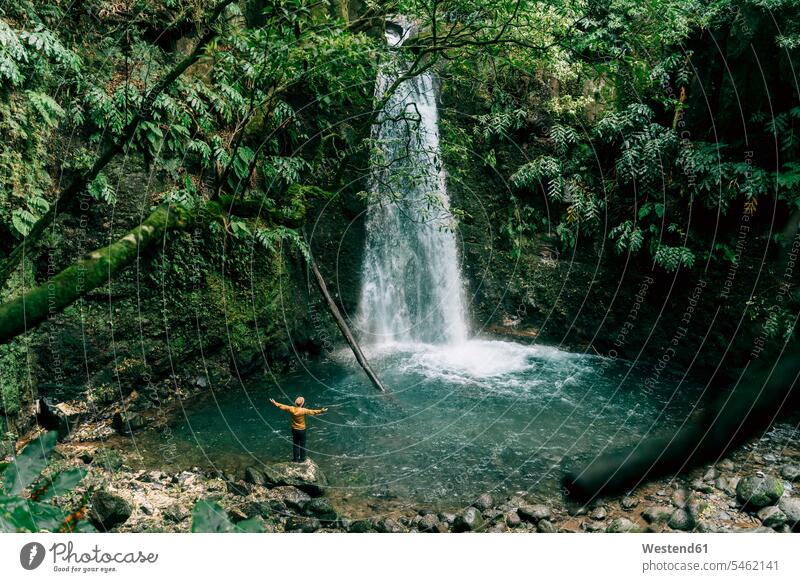 Rückansicht eines Mannes an einem Wasserfall auf der Insel Sao Miguel, Azoren, Portugal Touristen geniessen Genuss stehend steht erforschen Erforschung erkunden