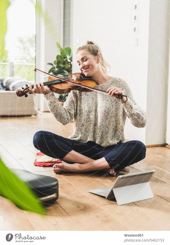 Frau mit Tablet sitzt auf dem Boden zu Hause spielen Geige Leute Menschen People Person Personen Alleinstehende Alleinstehender Singles Unverheiratete