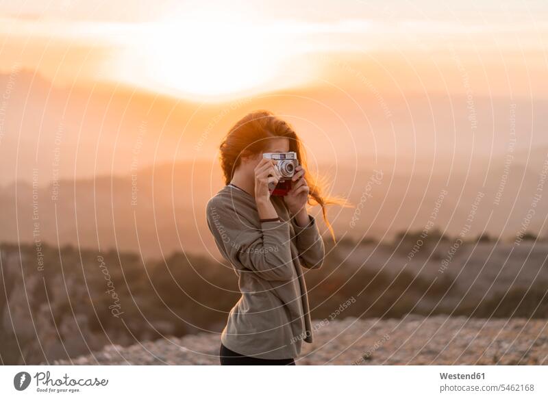 Spanien, Barcelona, Naturpark von Sant Llorenc, Frau nimmt ein Bild mit Vintage-Kamera bei Sonnenuntergang weiblich Frauen Kameras fotografieren