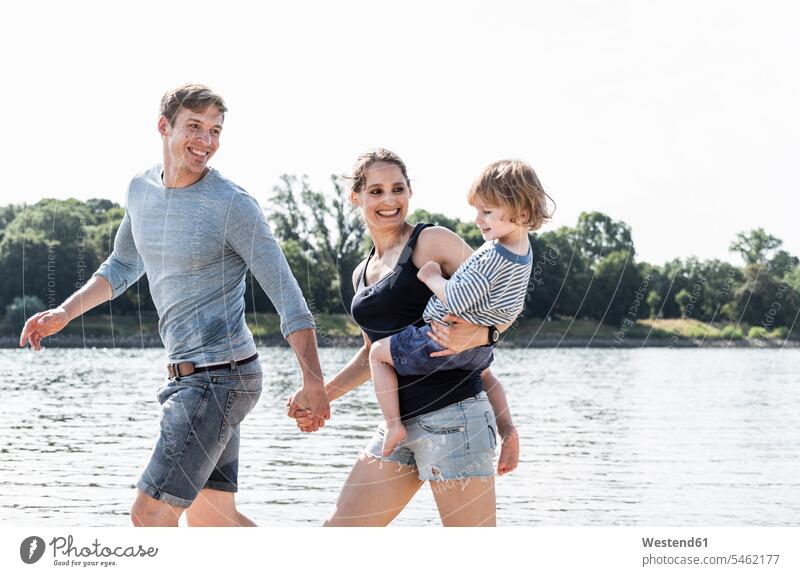 Glückliche Familie beim Spaziergang am Flussufer an einem schönen Sommertag gehen gehend geht glücklich glücklich sein glücklichsein Sommerzeit sommerlich Ufer
