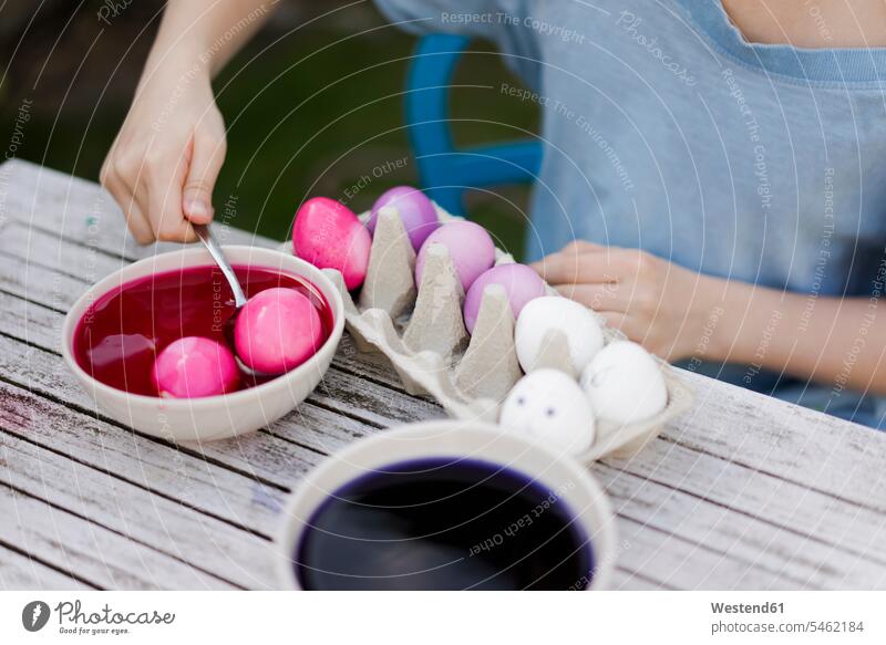 Nahaufnahme eines Mädchens beim Färben von Ostereiern im Garten Schale Schalen Schälchen Schüsseln Tische sitzend sitzt Frühjahr Lenz Farben Farbtoene Farbton