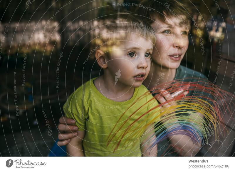 Porträt einer Mutter und ihres kleinen Sohnes, die mit gezeichneten Regenbogen aus dem Fenster schauen Leute Menschen People Person Personen Familien Mama Mamas