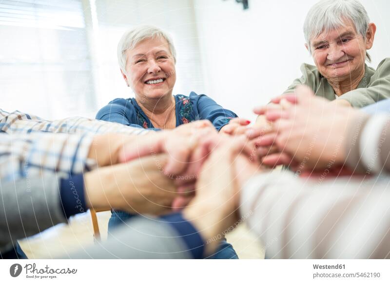 Gruppe aktiver Senioren, die sich die Hände reichen, als Symbol der Solidarität Europäer fünf Personen Seniorin 65-70 Jahre 70-80 Jahre reife Frau 55-60 Jahre