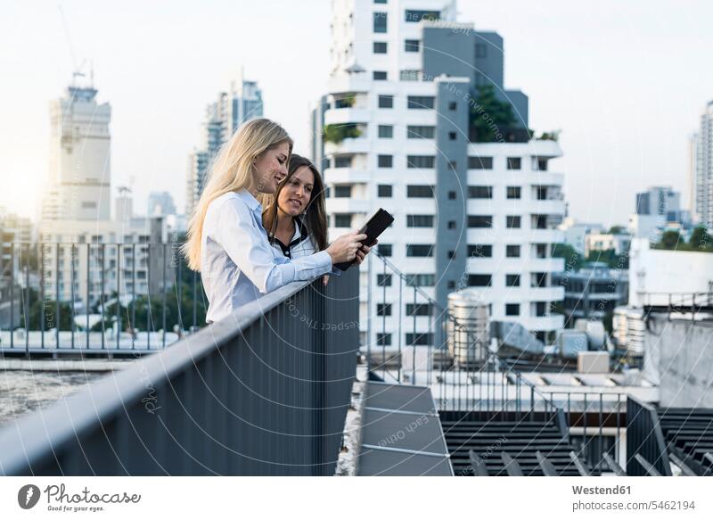 Zwei Geschäftsfrauen im Gespräch auf dem Dach der Stadt, mit digitalem Tablet Geschäftsleute Geschäftspersonen Businesswomen Businessfrauen Businesswoman