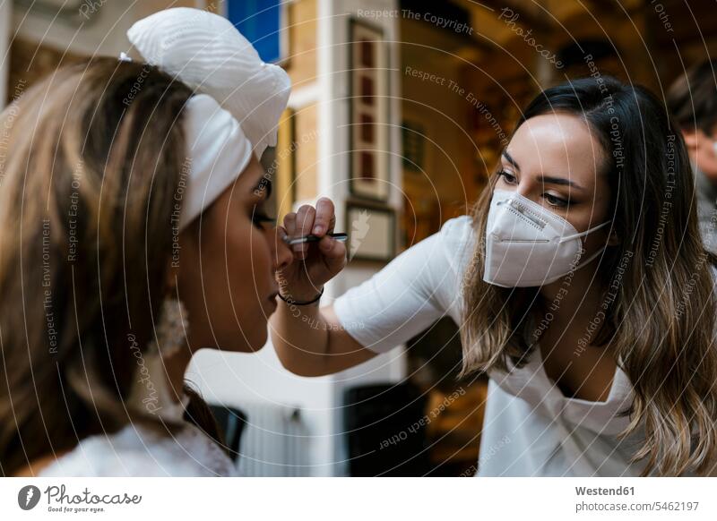 Junge Stylistin schminkt Teenager-Braut im Salon während COVID-19 Farbaufnahme Farbe Farbfoto Farbphoto Innenaufnahme Innenaufnahmen innen drinnen 16-17 Jahre