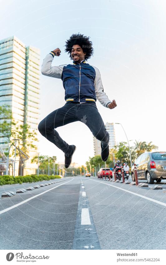 Glücklicher lässiger Mann, der in der Stadt springt, Barcelona, Spanien Freunde Kameradschaft Jacken Jubel gewinnen abends freuen Frohsinn Fröhlichkeit
