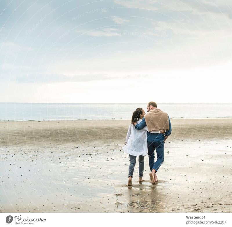 Reifes Paar mit umarmenden Armen genießt Wochenende am Strand bei bewölktem Himmel Farbaufnahme Farbe Farbfoto Farbphoto Niederlande Holland