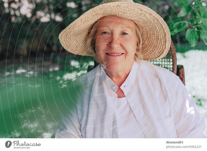 Nahaufnahme einer lächelnden älteren Frau mit Hut, die auf einem Stuhl im Hof sitzt Farbaufnahme Farbe Farbfoto Farbphoto Spanien Freizeitbeschäftigung Muße