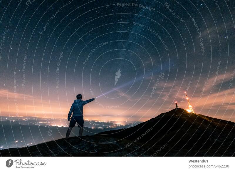 Italien, Monte Nerone, Silhouette eines Mannes mit Fackel unter Nachthimmel mit Sternen und Milchstraße Umriß Gegenlicht Schattenbilder Silhouetten Konturen