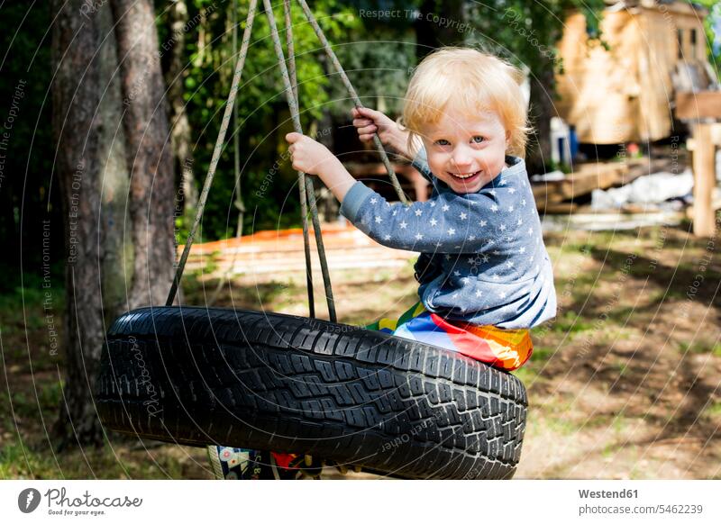 Porträt eines glücklichen Kleinkindes auf Reifenschaukel sitzend Seile Schaukeln sitzt freuen Glück glücklich sein glücklichsein Formen Sterne sternfoermig