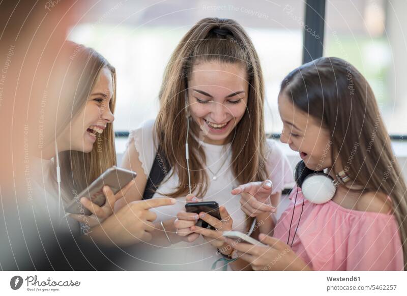 Glückliche Teenager-Mädchen benutzen Mobiltelefone in der Schule Schulen Schüler Handy Handies Handys glücklich glücklich sein glücklichsein Jugendliche
