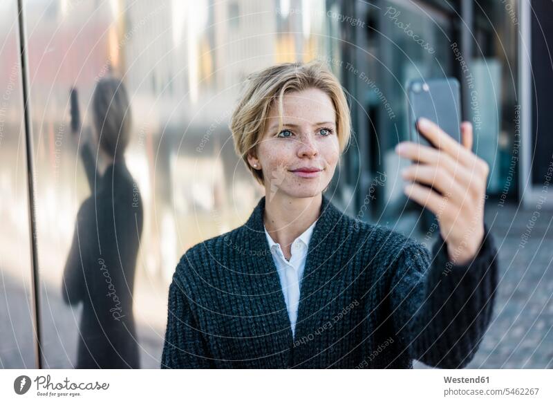 Junge Geschäftsfrau macht Selfie mit ihrem Smartphone Selfies benutzen benützen fotografieren lächeln junge Frau junge Frauen iPhone Smartphones weiblich