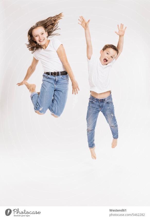 Fröhliche Geschwister springen vor weißem Hintergrund Farbaufnahme Farbe Farbfoto Farbphoto Freizeitkleidung Freizeitbekleidung casual weißer Hintergrund