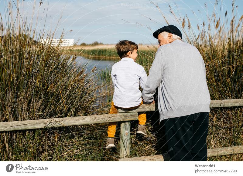 Rückenansicht eines kleinen Jungen und seines Großvaters, die sich gegenseitig ansehen Spanien gute Laune Betreuung betreuen ländliches Motiv nicht städtisch