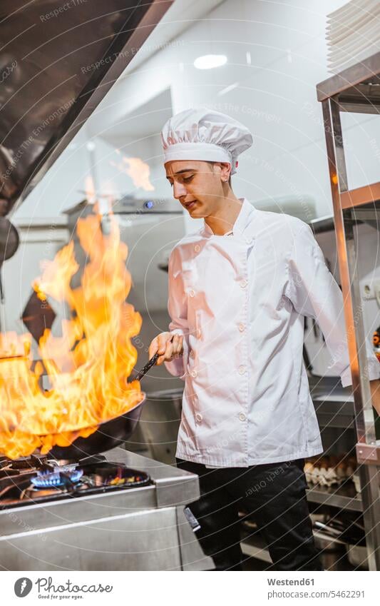 Junior-Chefkoch mit Flammenpfanne in traditioneller spanischer Restaurantküche Leute Menschen People Person Personen Europäisch Kaukasier kaukasisch 1 Ein