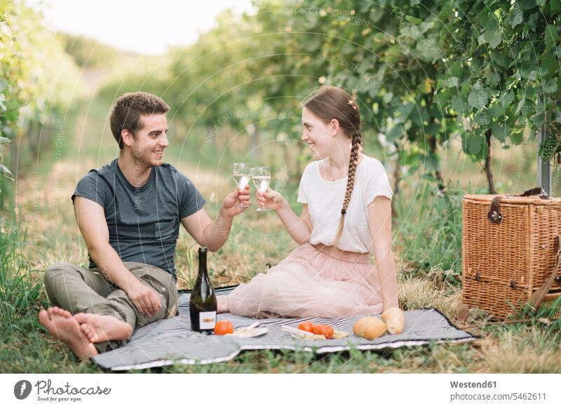 Glückliches junges Paar beim Picknick in den Weinbergen, beim Prosecco-Toast sitzend sitzt freuen glücklich sein glücklichsein gefühlvoll Emotionen Empfindung