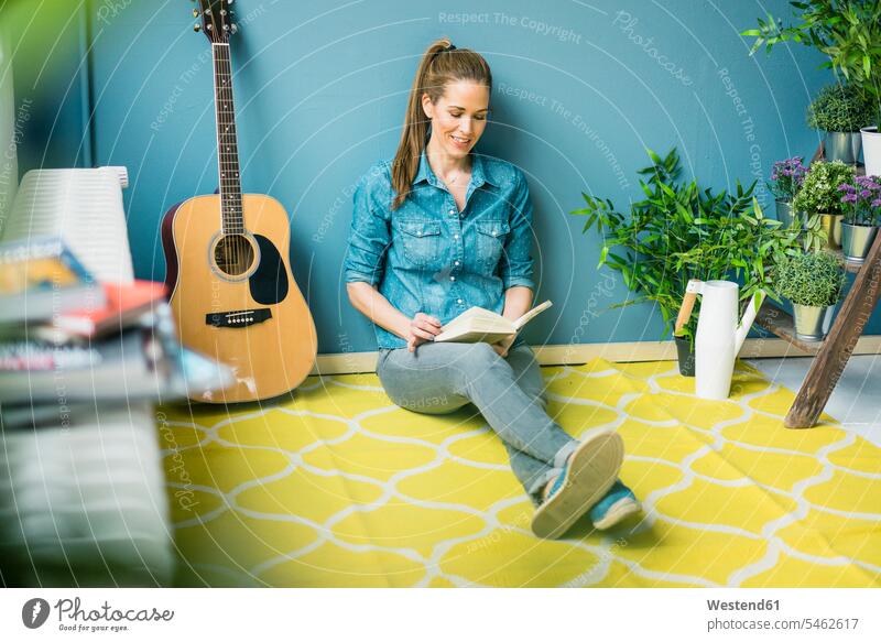 Frau entspannt sich in ihrem Haus mit Topfpflanzen und liest ein Buch Entspannung Entspannen relaxen entspannen Zuhause zu Hause daheim weiblich Frauen sitzen