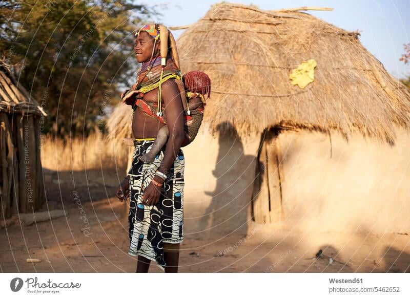 Frau vom Stamm der Muhila, die ihr Kind auf dem Rücken trägt, Kehamba, Chibia, Angola Doerfer Dörfer Brauchtum traditionell Bauwerke Gebäude Hütten