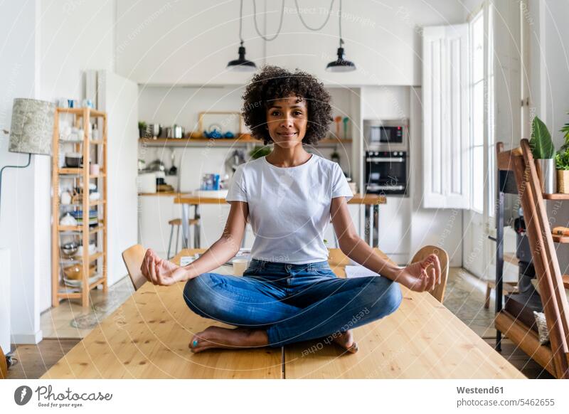 Porträt der lächelnden Frau in Yoga-Pose auf dem Tisch zu Hause weiblich Frauen Zuhause daheim Yoga-Übungen Yogauebungen Yogaübungen Jogauebung Jogauebungen