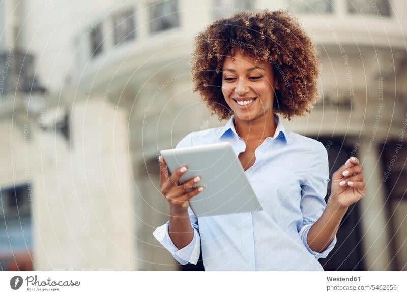 Lächelnde Frau mit Afro-Frisur mit Tablette in der Stadt Tablet Computer Tablet-PC Tablet PC iPad Tablet-Computer lächeln weiblich Frauen Afro-Look Afros