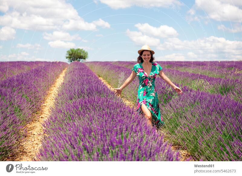 Frankreich, Provence, Valensole Plateau, lächelnde Frau zu Fuß zwischen Lavendelfeldern im Sommer gehen gehend geht weiblich Frauen Feld Felder Erwachsener