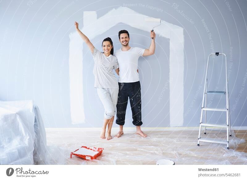 Porträt eines fröhlichen Paares malt in neuer Wohnung mit Hausform an der Wand Portrait Porträts Portraits Form Formen glücklich Glück glücklich sein