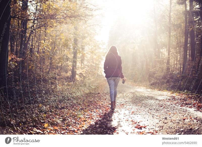 Rückenansicht einer jungen Frau beim Waldspaziergang im Herbst entspannen relaxen Jahreszeiten Muße auf Achse in Bewegung alleine einzeln bewegen sich bewegen