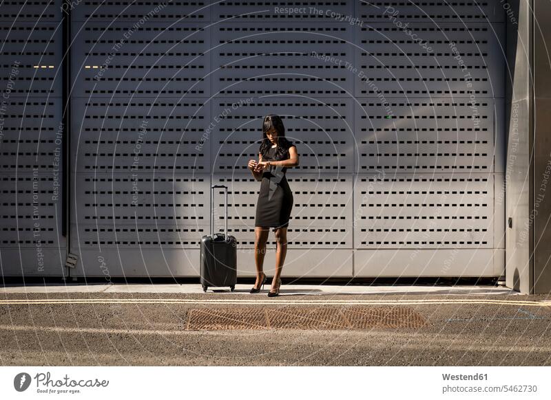 Geschäftsfrau mit Einkaufswagen, die die Zeit überprüft Leute Menschen People Person Personen Afrikanisch Afrikanische Abstammung dunkelhäutig Farbige Farbiger