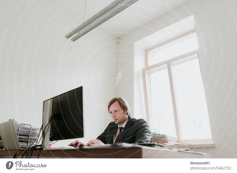 Geschäftsmann mit Computer am Schreibtisch im Büro Europäer Kaukasier Europäisch kaukasisch Tag am Tag Tageslichtaufnahme tagsueber Tagesaufnahmen