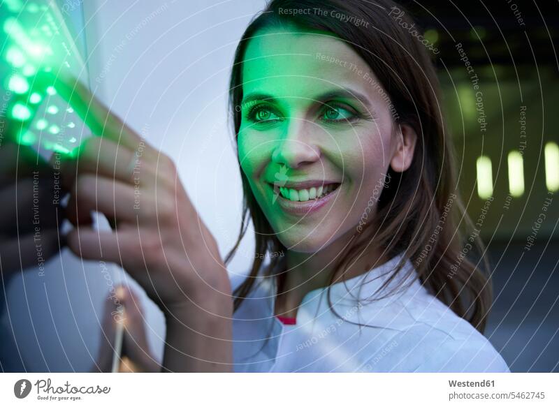 Nahaufnahme einer lächelnden Frau, die einen Touchscreen mit grüner LED berührt Koepfe Köpfe Gesichter Beleuchtungen anfassen Berührung zufrieden Farben