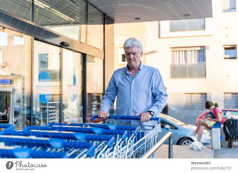 Älterer Mann nimmt Einkaufswagen im Supermarkt Leute Menschen People Person Personen Europäisch Kaukasier kaukasisch 1 ein Mensch eine nur eine Person single