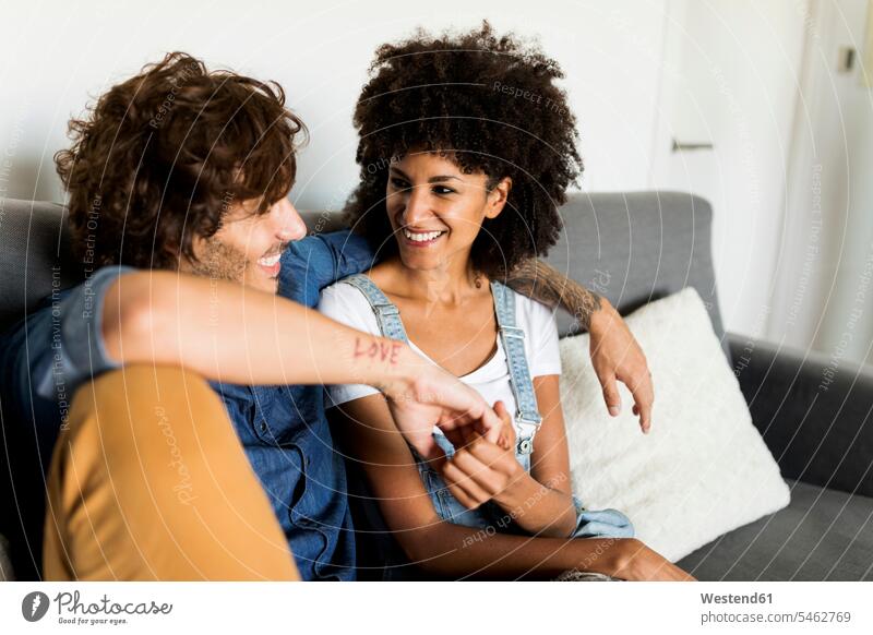 Glückliches Paar sitzt auf der Couch und spricht Pärchen Paare Partnerschaft sprechen reden Sofa Couches Liege Sofas glücklich glücklich sein glücklichsein