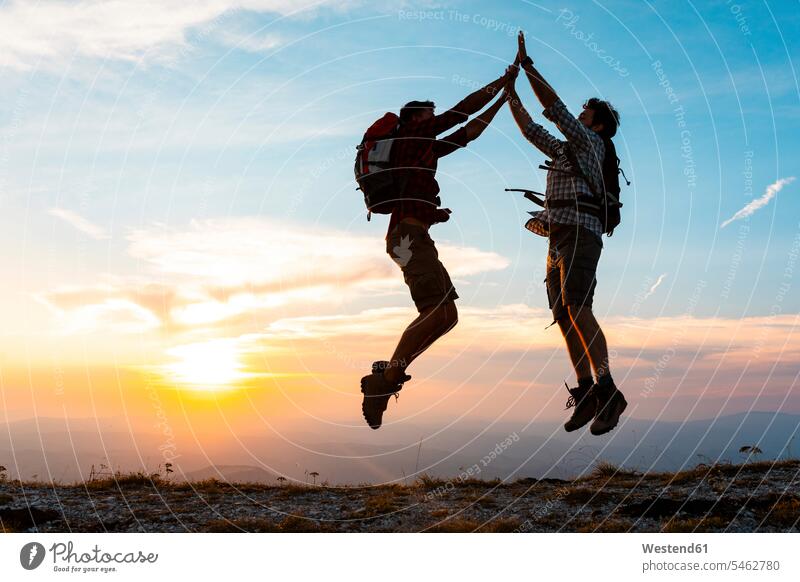 Italien, Monte Nerone, zwei glückliche und erfolgreiche Wanderer springen bei Sonnenuntergang in die Berge Sonnenuntergänge hüpfen Glück glücklich sein