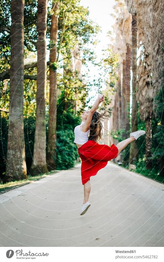 Junge Frau springt beim Tanzen auf der Straße zwischen Bäumen im Park Farbaufnahme Farbe Farbfoto Farbphoto Portugal Freizeitbeschäftigung Muße Zeit Zeit haben