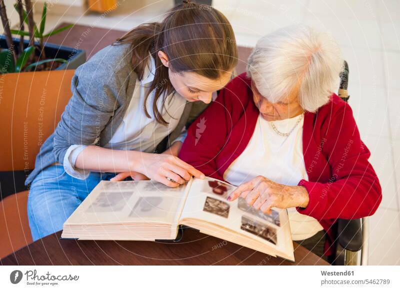 Großmutter mit Enkelin schaut Fotoalbum zu Hause Farbaufnahme Farbe Farbfoto Farbphoto Deutschland Innenaufnahme Innenaufnahmen innen drinnen