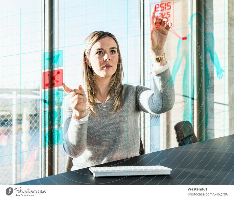 Junge Geschäftsfrau berührt Projektionsschirm mit Daten im Büro Geschäftsfrauen Businesswomen Businessfrauen Businesswoman Office Büros berühren Berührung