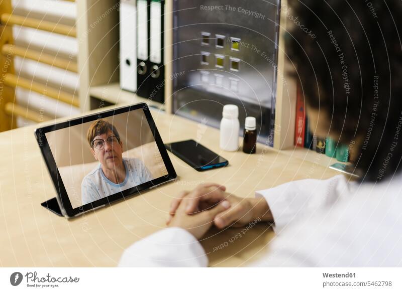 Ältere Frau auf digitalem Tablet-Bildschirm während Videoanruf mit Arzt Farbaufnahme Farbe Farbfoto Farbphoto Spanien Innenaufnahme Innenaufnahmen innen drinnen
