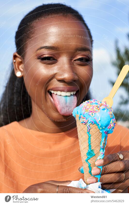 Porträt einer jungen Frau mit hellblauem Eis, das die Zunge herausstreckt Zungen weiblich Frauen herausstrecken herausgestreckt Portrait Porträts Portraits Mund