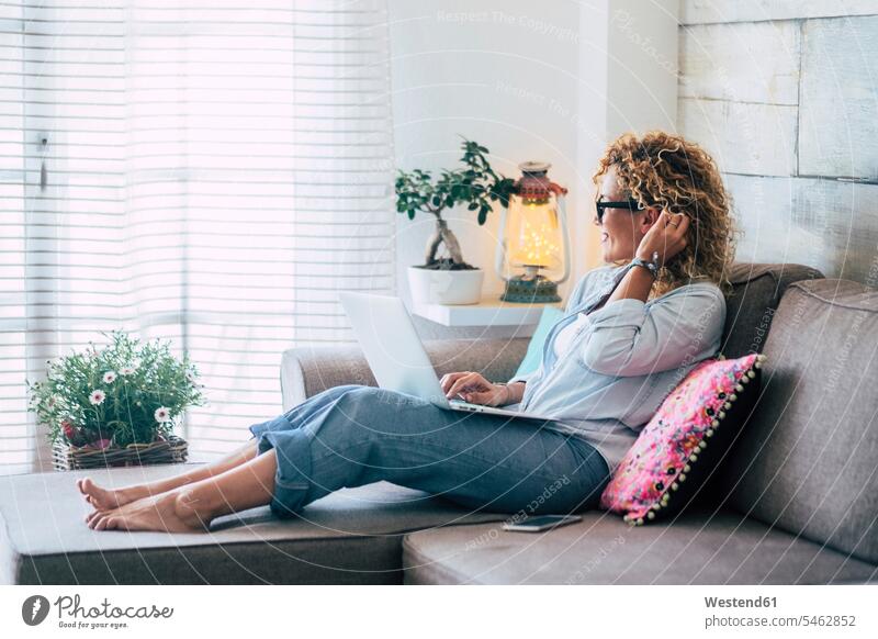 Frau mit Laptop auf der Couch zu Hause Gefärbtes Haar Gefärbte Haare weiblich Frauen eine Person single 1 ein Mensch einzelne Person Ein nur eine Person