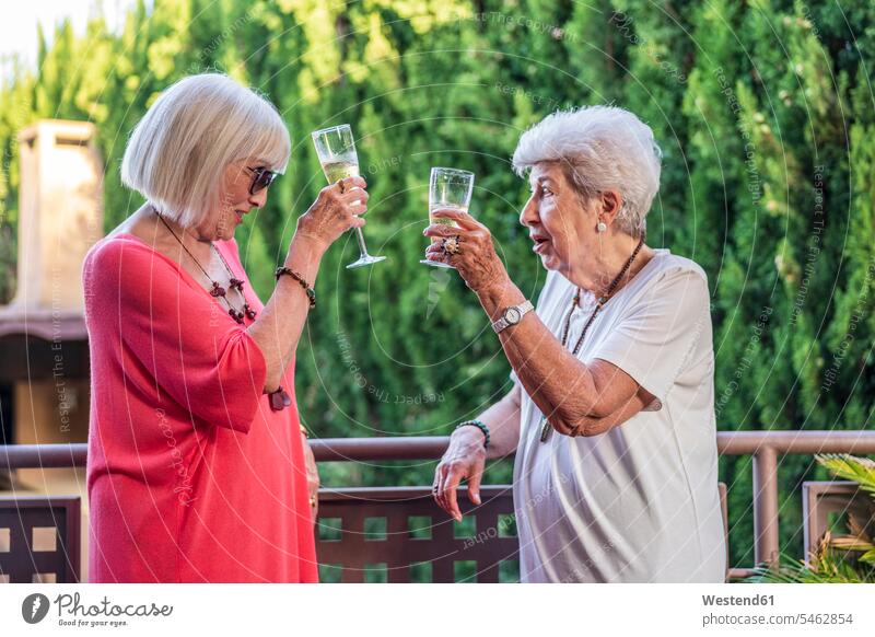 Ältere Freundinnen stoßen auf Champagnerflöten an, während sie am Balkongeländer stehen Farbaufnahme Farbe Farbfoto Farbphoto Spanien Freizeitbeschäftigung Muße