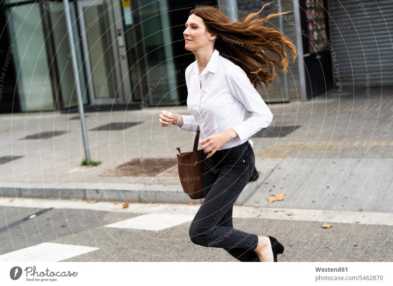 Geschäftsfrau läuft auf der Straße Städtische Straße Strassen Straßen unterwegs auf Achse in Bewegung Urban städtisch Urbanität Urbanitaet schnell Schnelligkeit