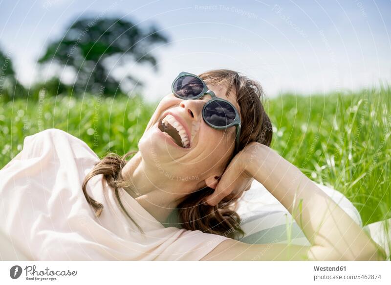 Porträt einer lachenden entspannten Frau, die auf einer Wiese liegt Leute Menschen People Person Personen erwachsen Erwachsene Frauen weiblich reife Frauen