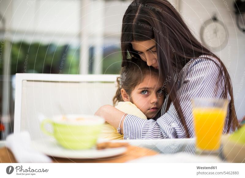 Mutter umarmt ihre traurige Tochter beim Frühstück zu Hause Zuhause daheim frühstücken Töchter Mami Mutti Mütter Mama umarmen Umarmung Umarmungen Arm umlegen